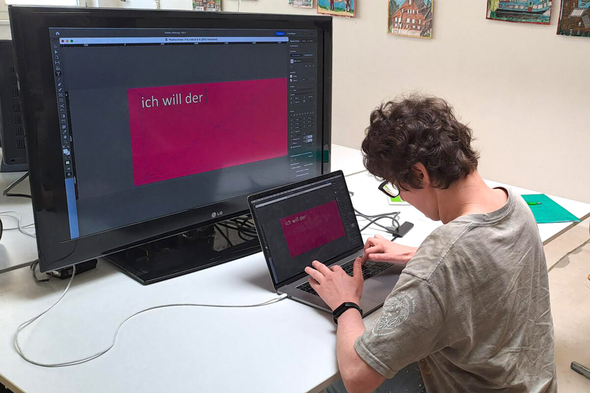 Eine Person schreibt am Computer den Text für ihr Plakat.